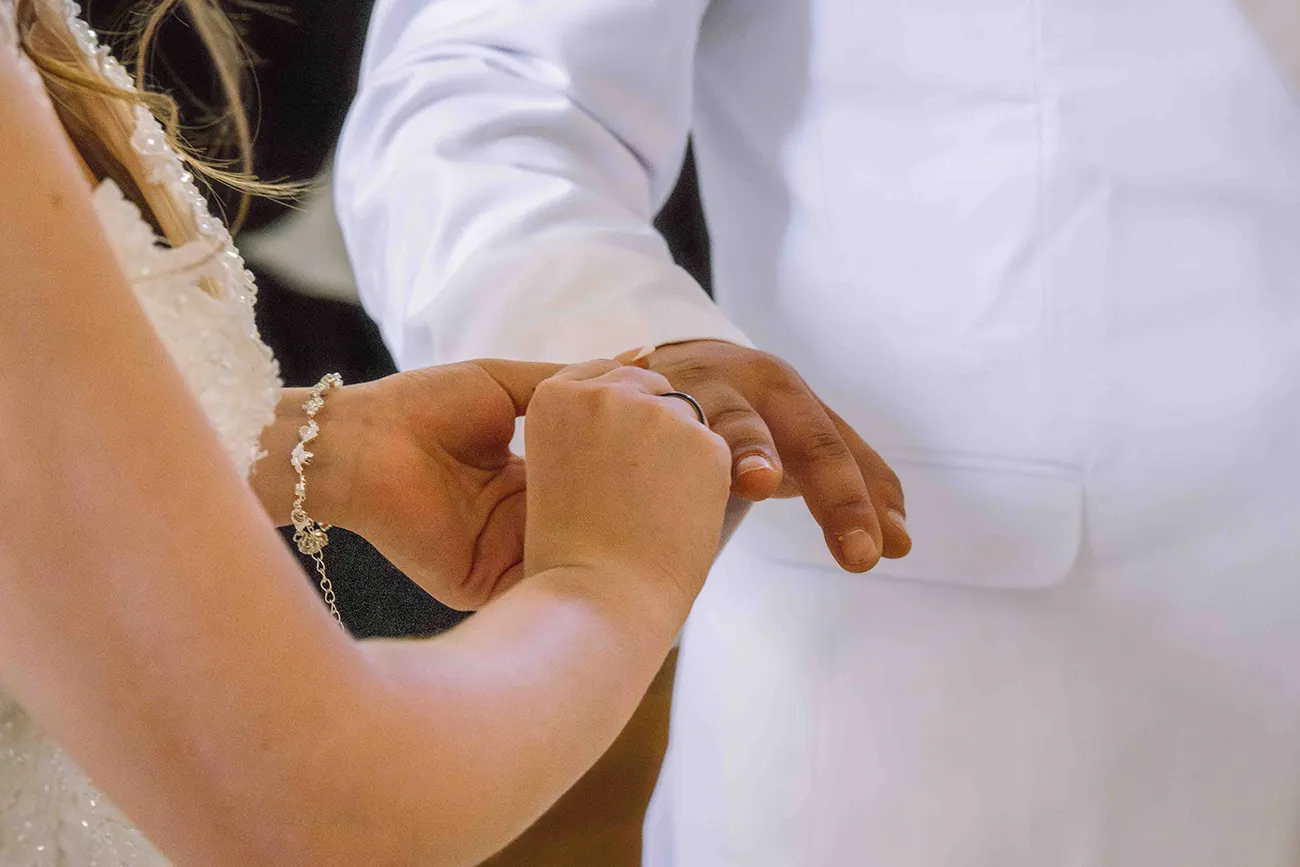 Hochzeitsreportage kirchliche Hochzeit, die Braut steckt den Bräutigam den Ehering an den Finger. Ringtausch
