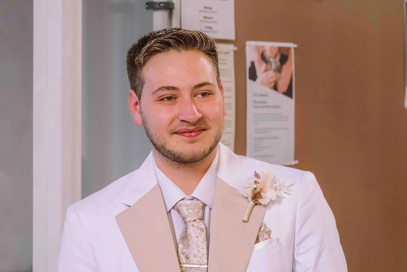 glücklich lächelnder Bräutigam im weissen Anzug nach der Trauung