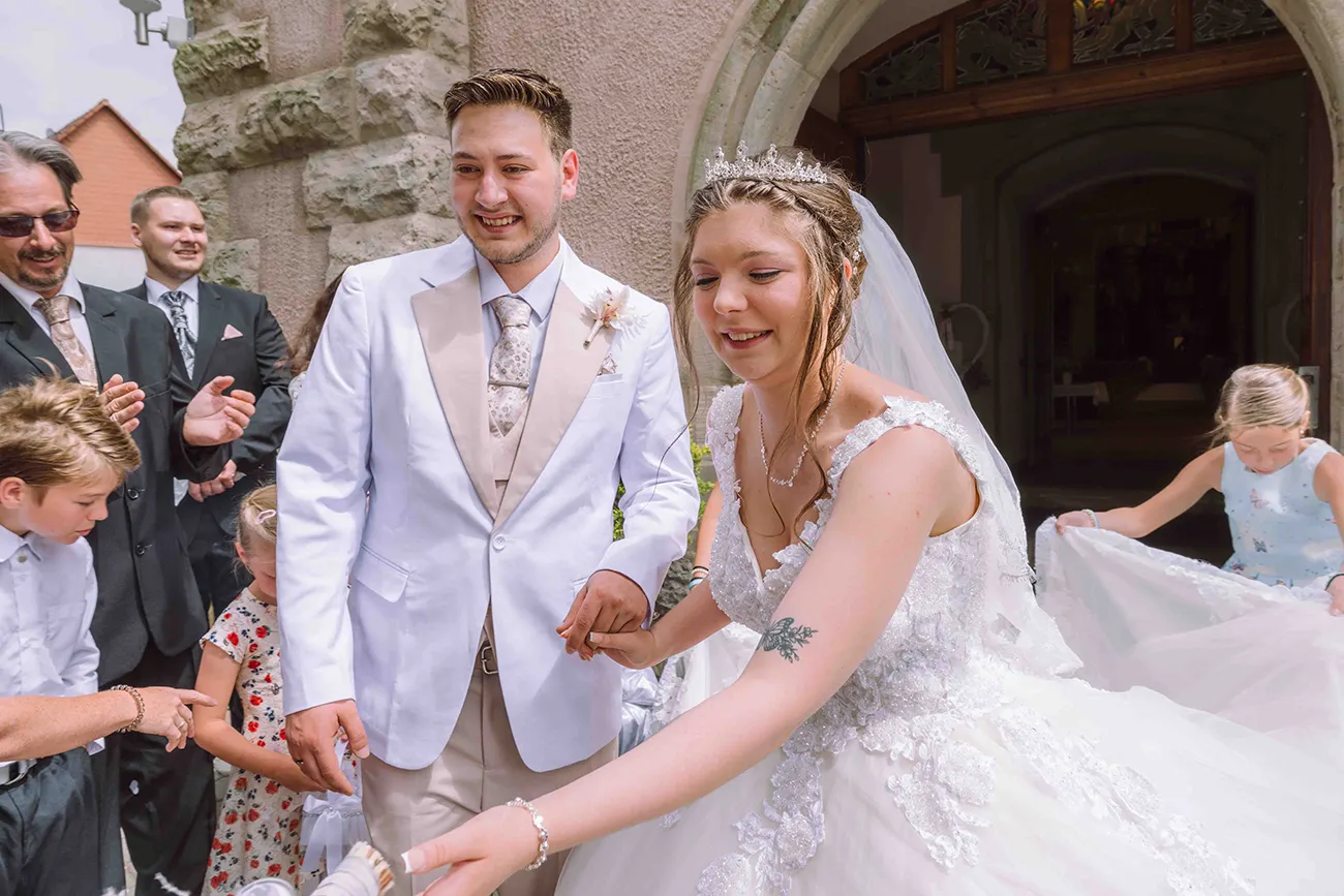 Das Brautpaar kommt aus der Kirche und erhält von der Hochzeitsgesellschaft und Gratulanten kleine Geschenke