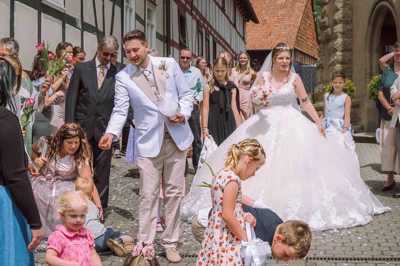 Das Brautpaar auf den Weg durch die Hochzeitsgesellschaft, Kinder streuen Blumen. Hochzeitsreportage