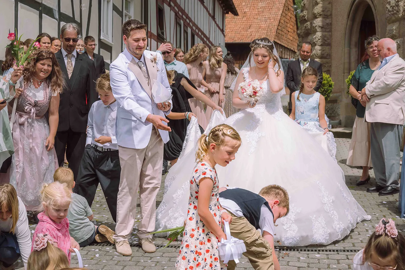 Das Brautpaar streut nach der kirchlichen Trauung Süssigkeiten für die Kinder. Die Blumenkinder gehen vorweg
