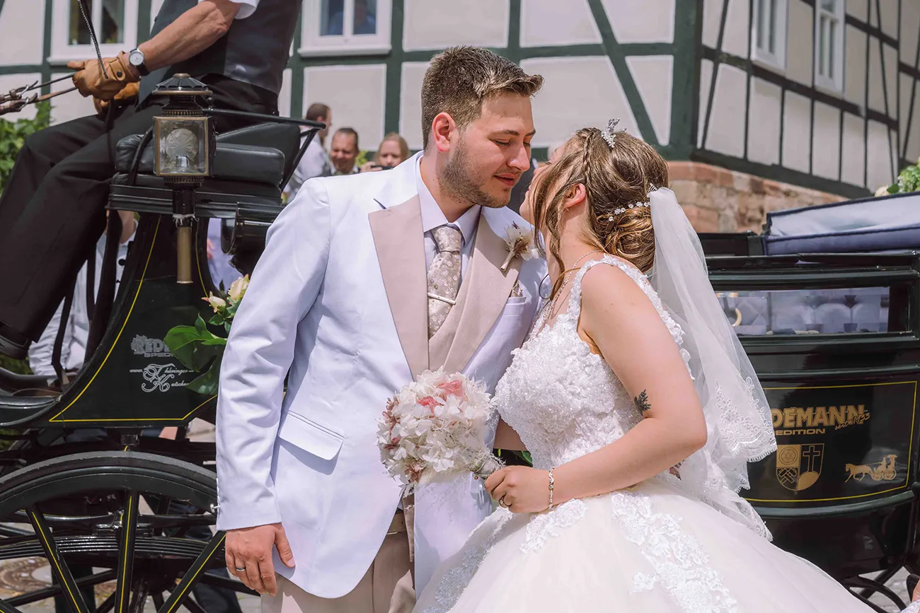 Hochzeitsreportage, küssendes Brautpaar vor Hochzeitskutsche