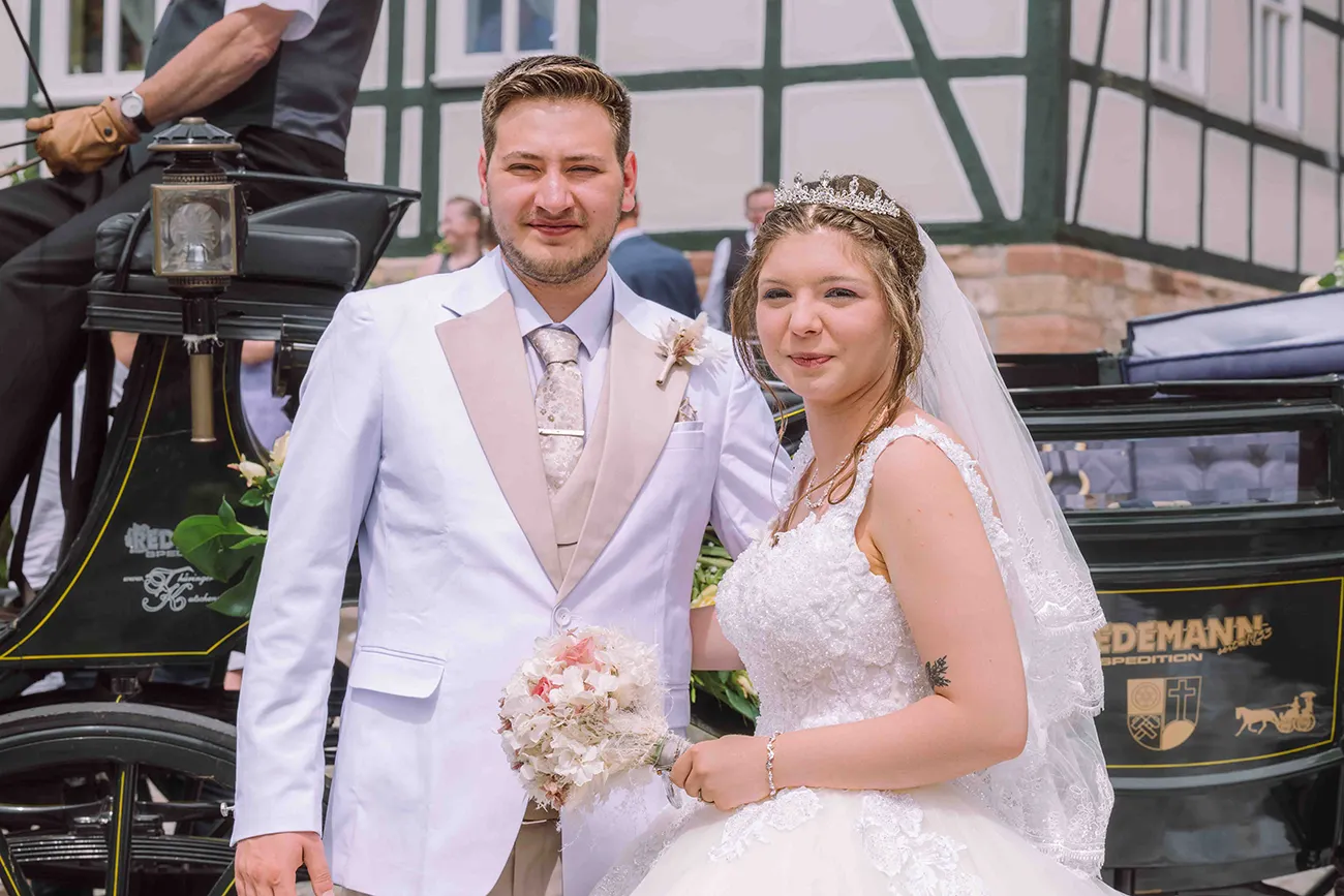 Das Brautpaar vor der Kutsche, mit blick zur Kamera