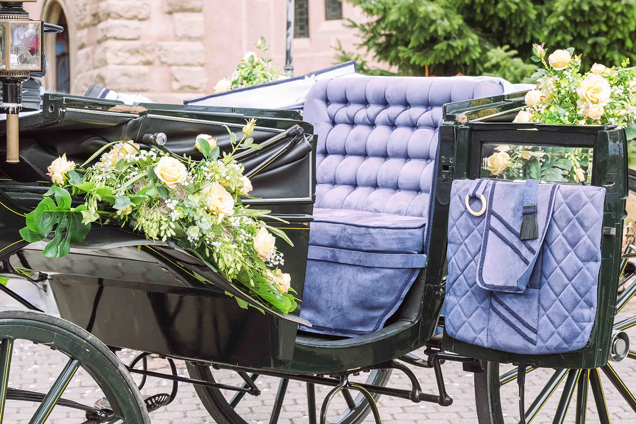 Die Hochzeitskutsche ist mit Blumen geschmückt und die Tür geöffnet. Die bequeme Bank ist zu sehen.