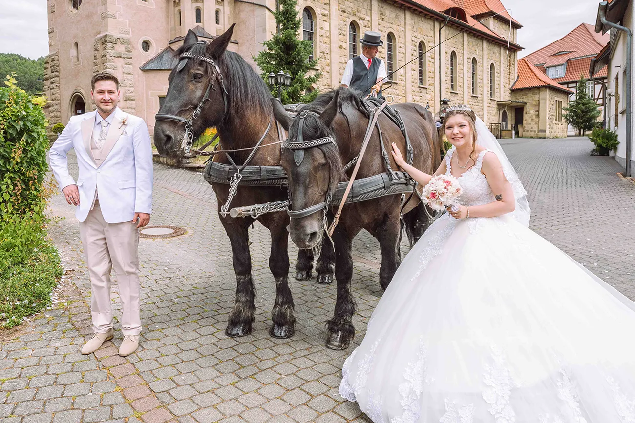 Das Brautpaar steht bei den Kutschpferden vor der Kutsche. Hochzeitsreportage in Thüringen