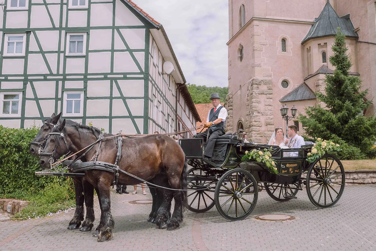 Das Brautpaar sitzt in der Kutsche vor der Kirche