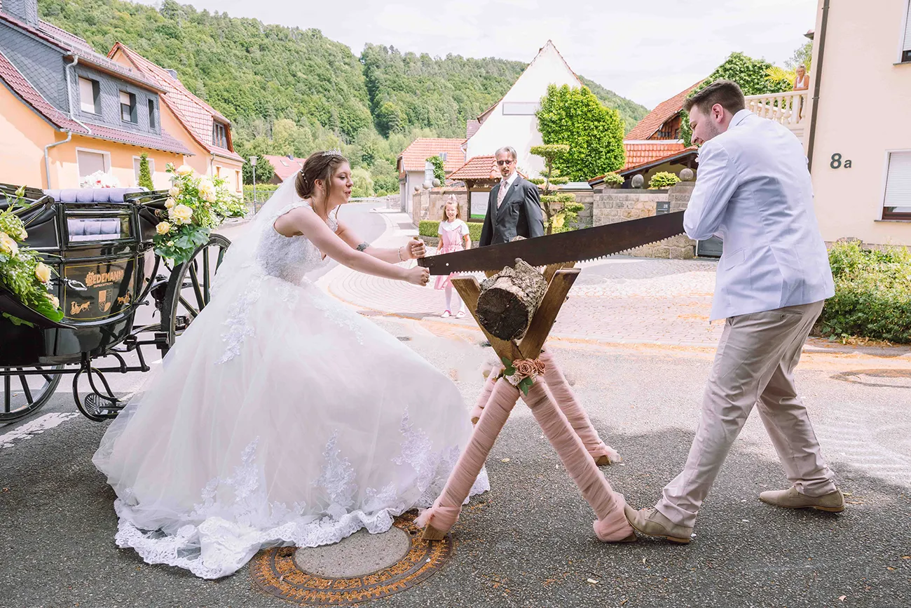 Ein Hochzeits- Ritual,Das Brautpaar sägt einen Baumstamm durch