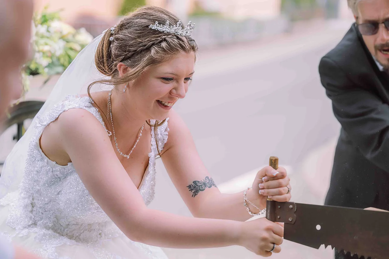 Hochzeitsfotografie, die Braut beim durchsägen eines Baumstamm