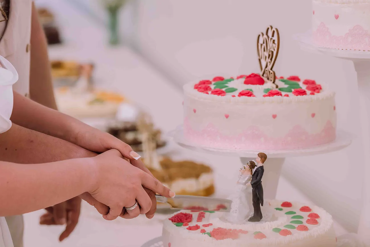 Hochzeitsreportage, Braut und Bräutigam schneiden gemeinsam die Hochzeitstorte an