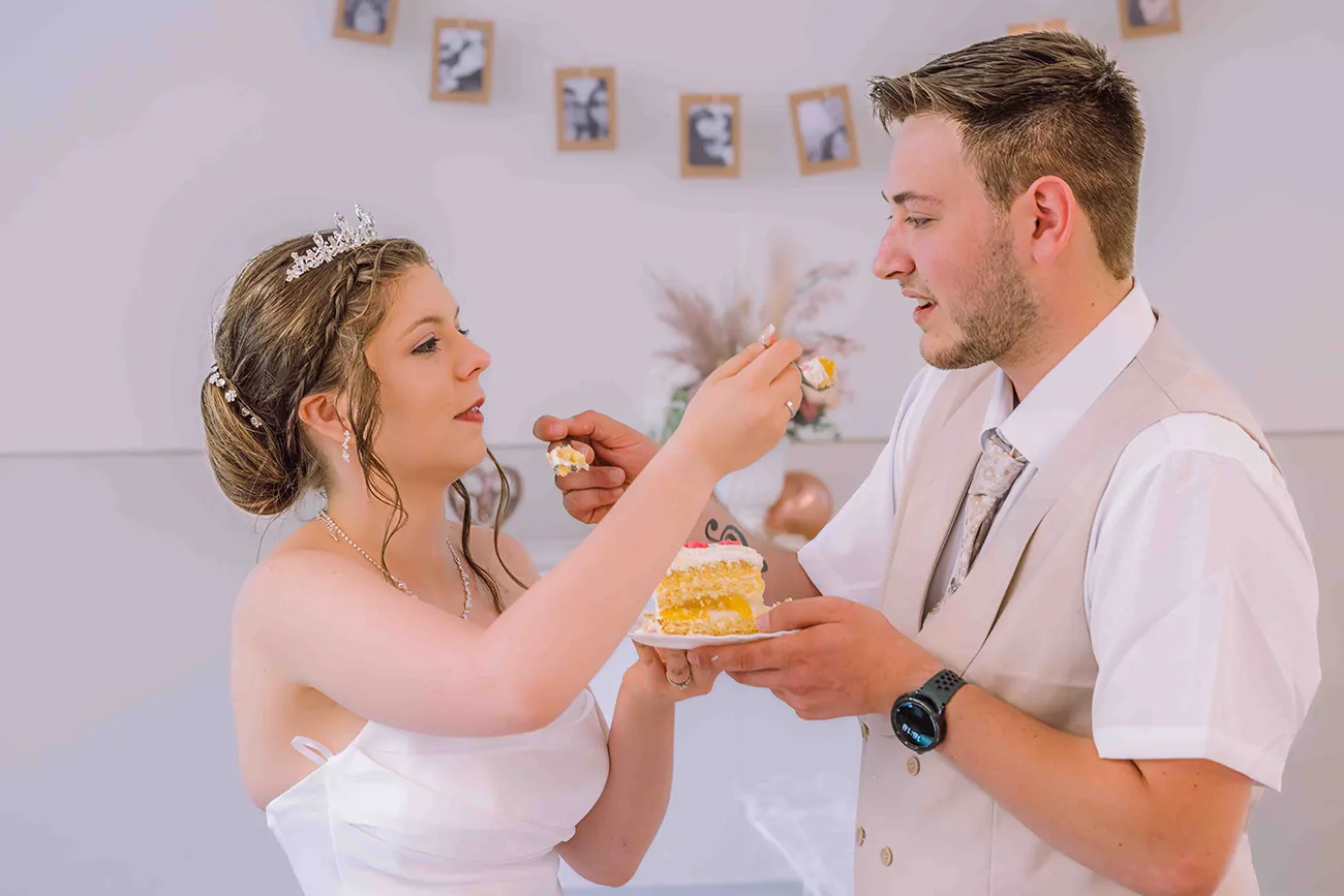 Hochzeitsreportage, Braut und Bräutigam reichen sich gegenseitig eine Gabel mit Hochzeitstorte