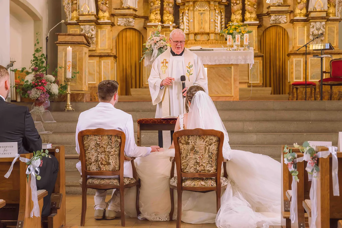 Brautpaar bei der kirchlichen Trauung, von hinten vor dem Pastor fotografiert