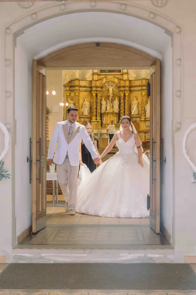 Brautpaar verlässt glücklich die Kirche nach der Trauung. Von außen in die Kirche fotografiert