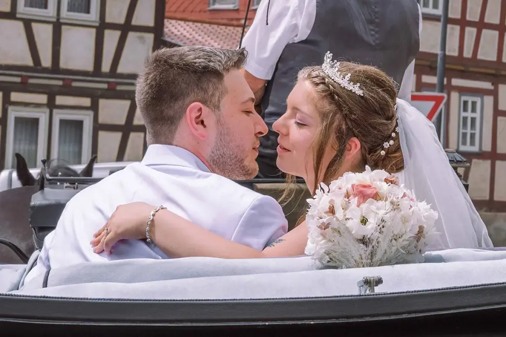 Das Brautpaar küsst sich beim Wegfahren nach der Kirche in der Kutsche, Hochzeitsreportage aus Thüringen