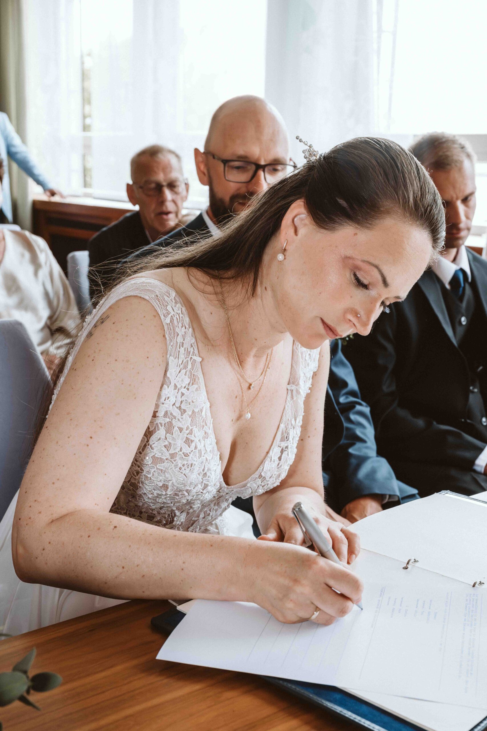 Hochzeitsreportage, die Braut unterzeichnet die Hochzeitsurkunde im Standesamt