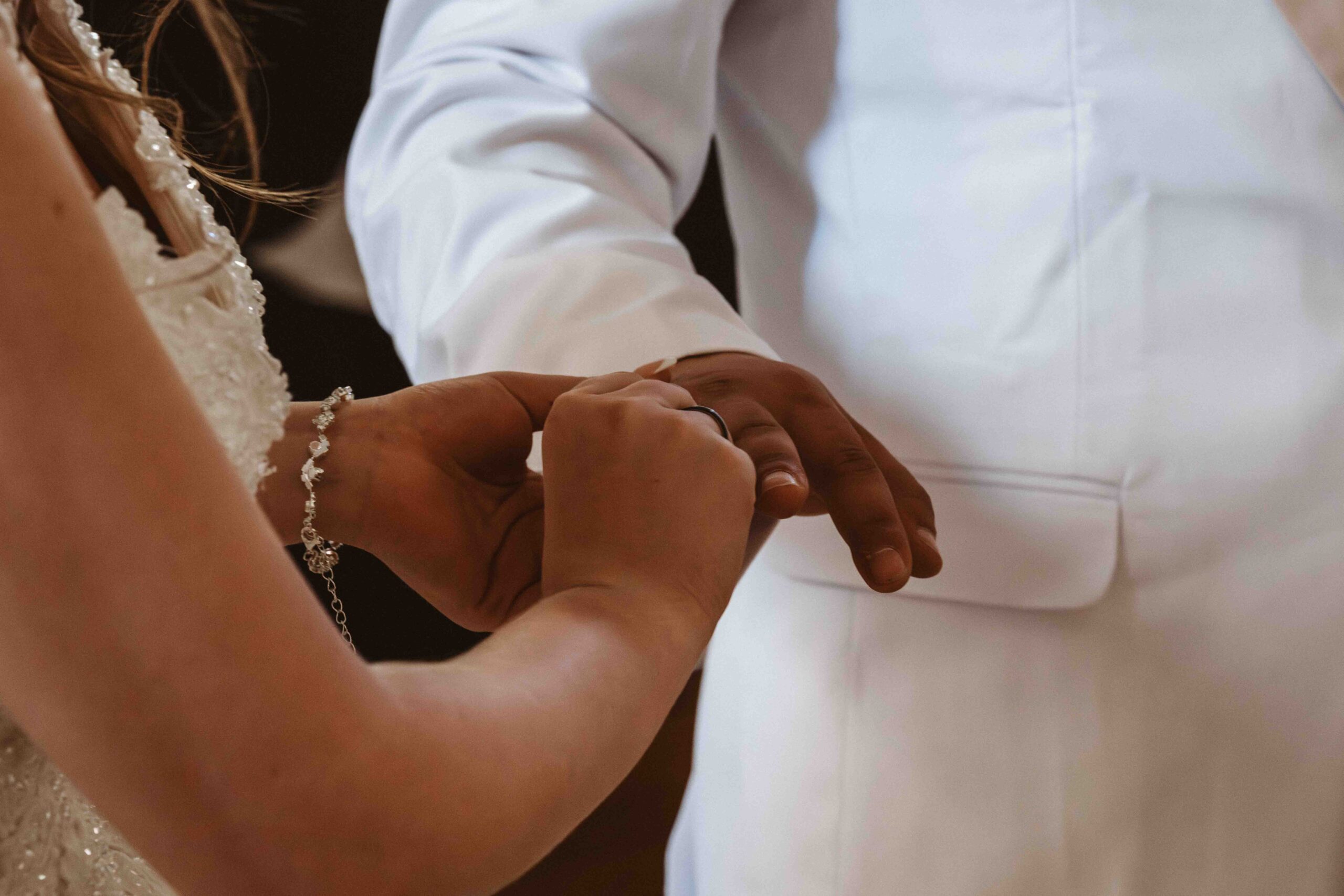 Hochzeitsreportage kirchliche Hochzeit, die Braut steckt den Bräutigam den Ehering an den Finger.