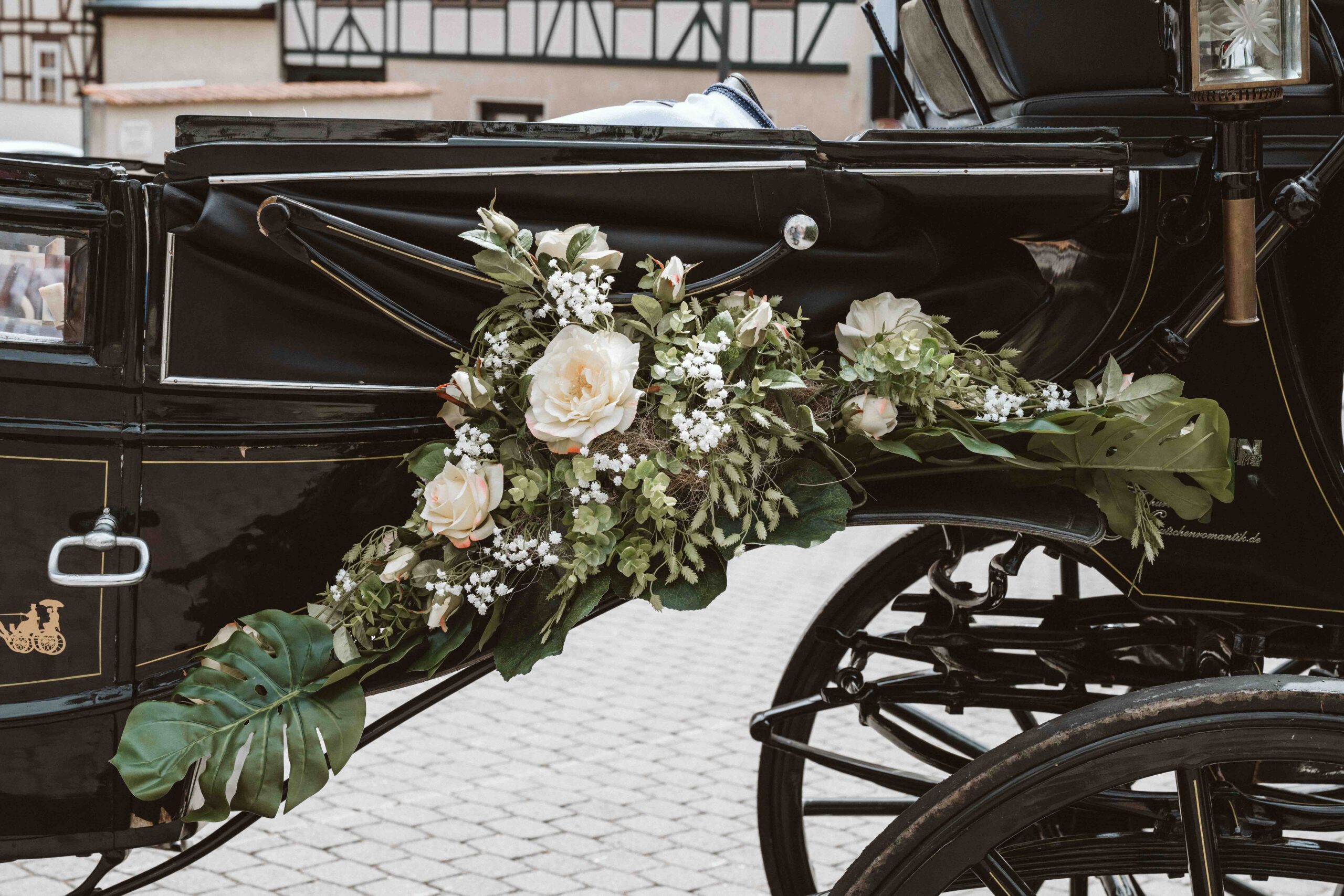 Mit Blumen und weißen Rosen verzierter Kotflügel der Hochzeitskutsche