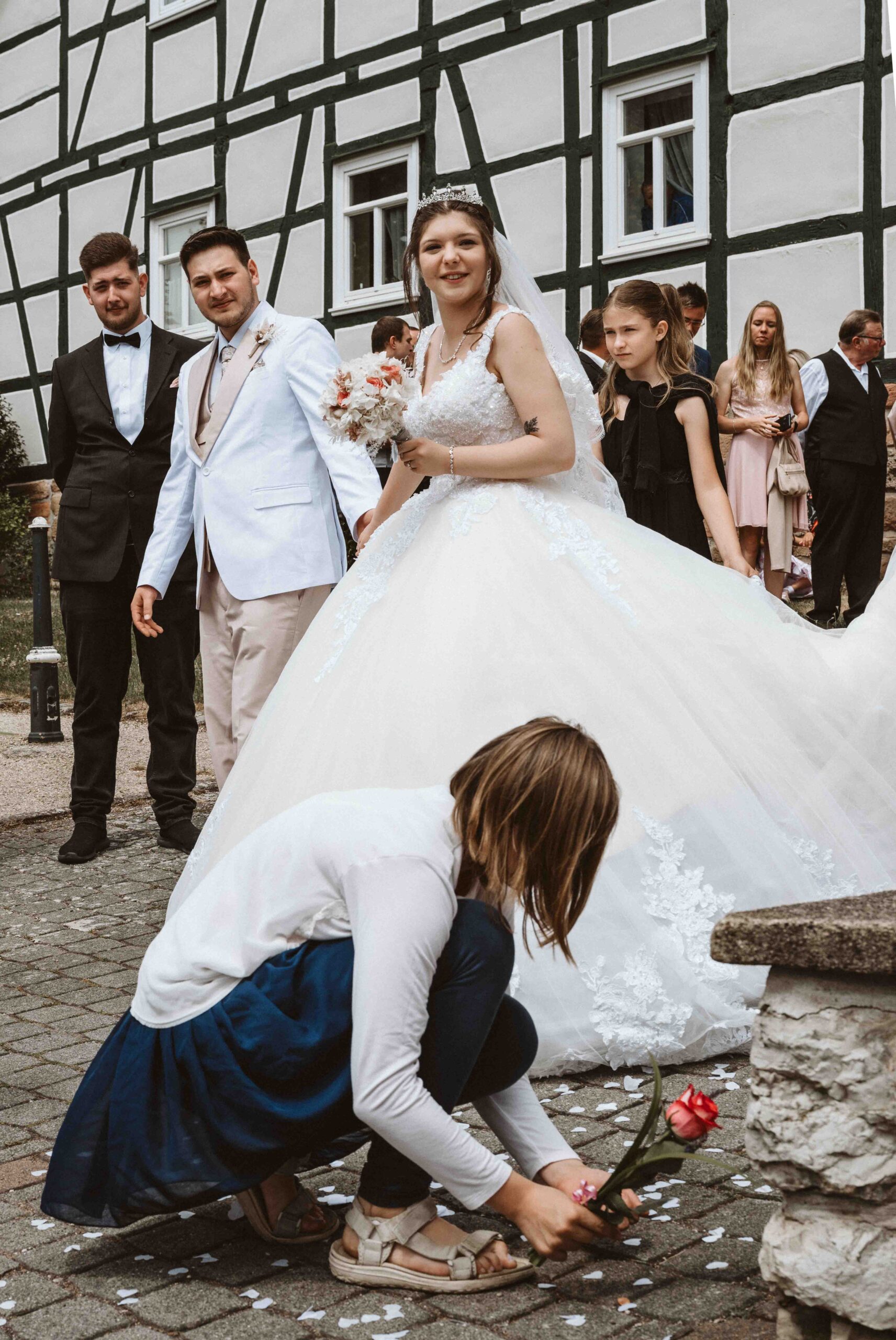 Hochzeitsreportage, das Brautpaar kommt aus der Kirche, mit Blumenkind im Vordergrund