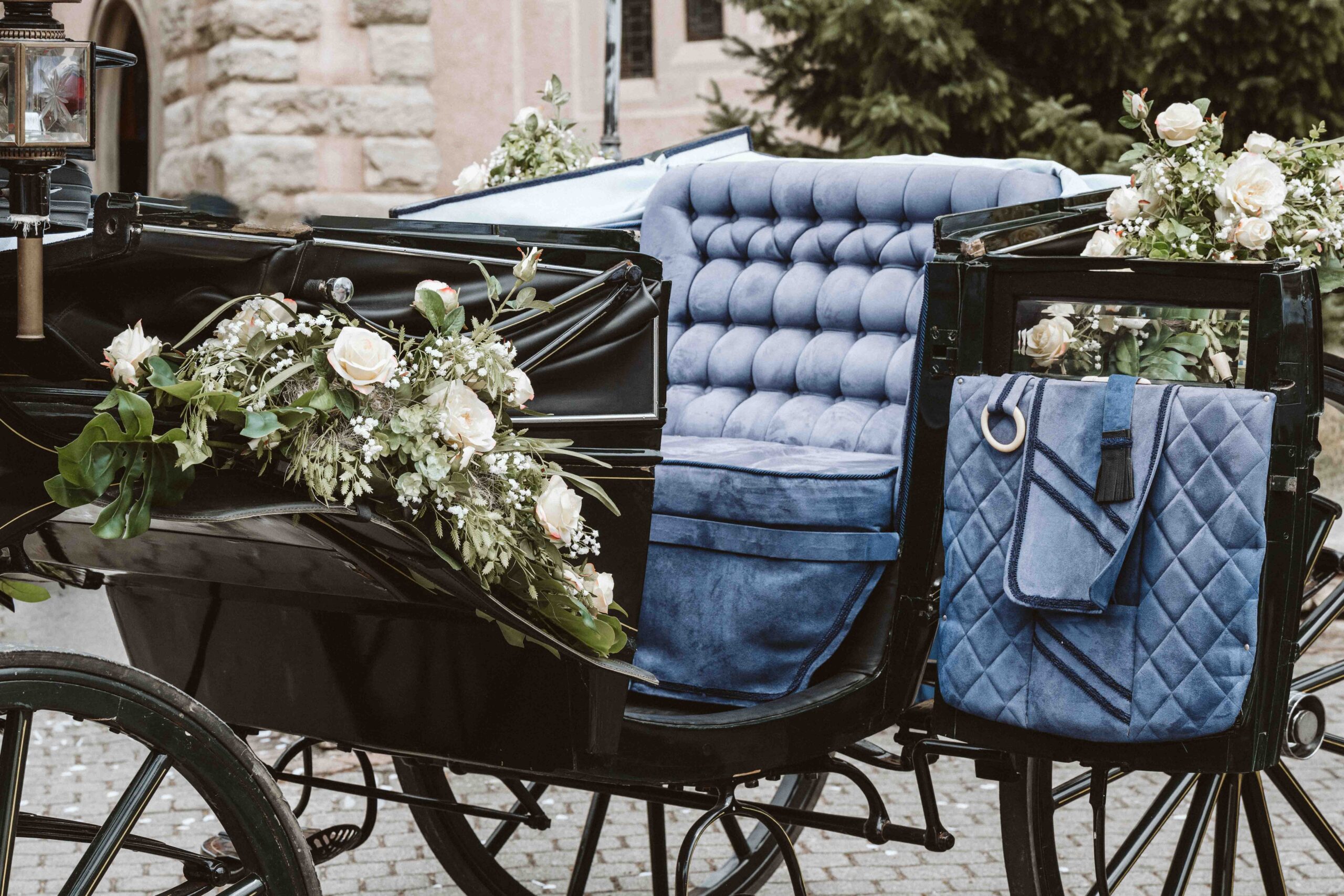 Die Hochzeitskutsche ist mit Blumen geschmückt und die Tür geöffnet. Die bequeme Bank ist zu sehen.