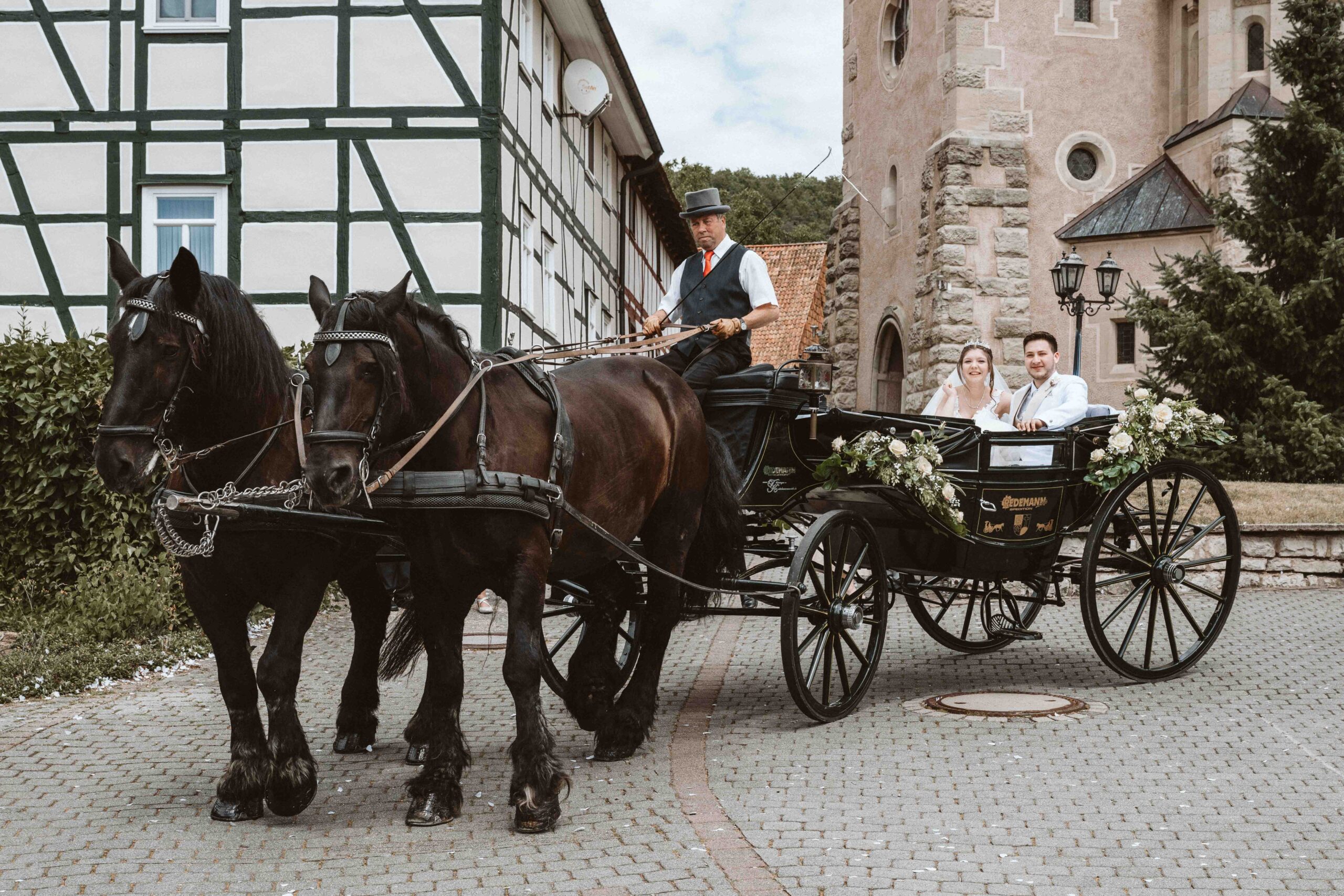 Das Brautpaar sitzt in der Kutsche vor der Kirche