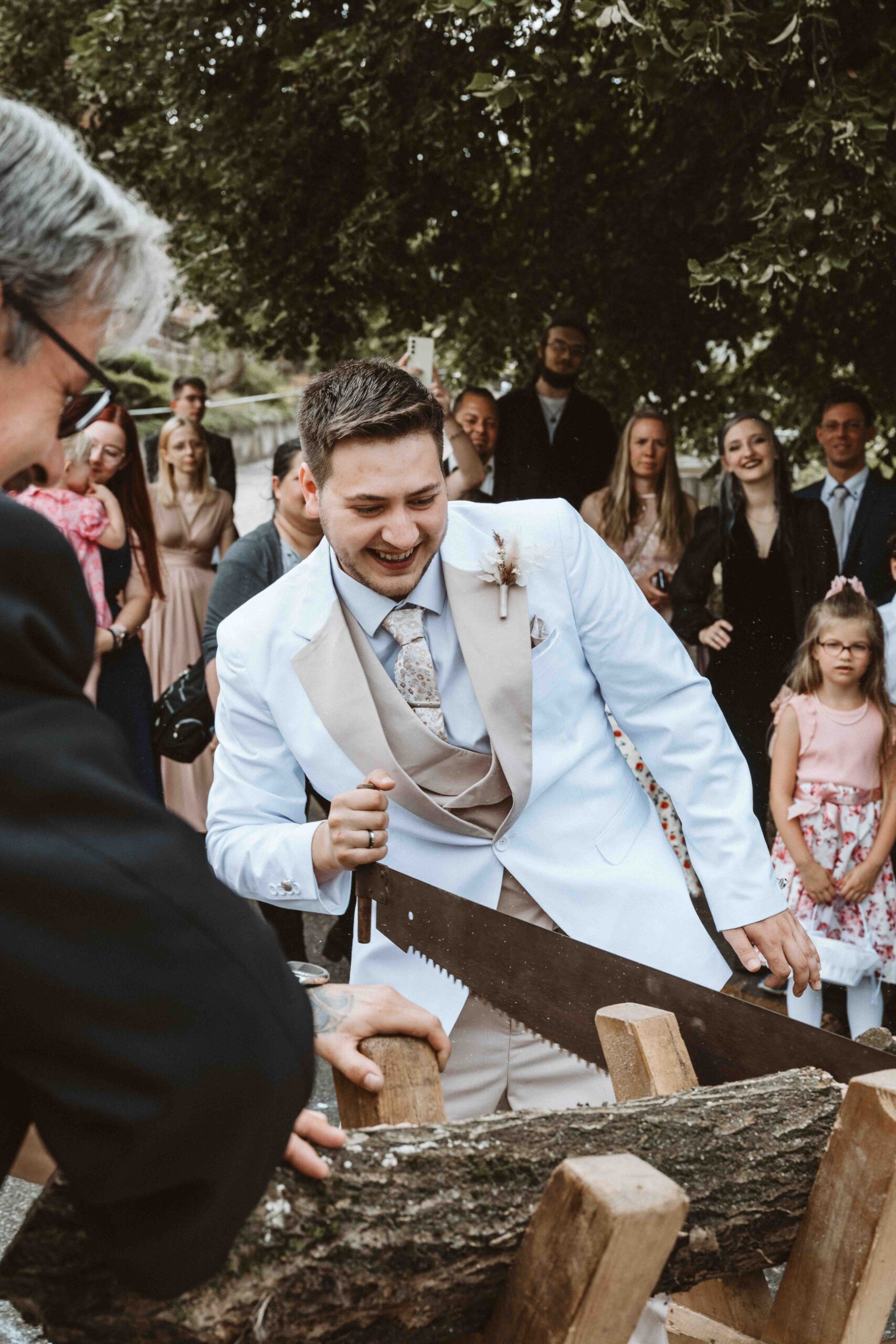 Hochzeitsreportage, der Bräutigam beim durchsägen einer Baumstamm