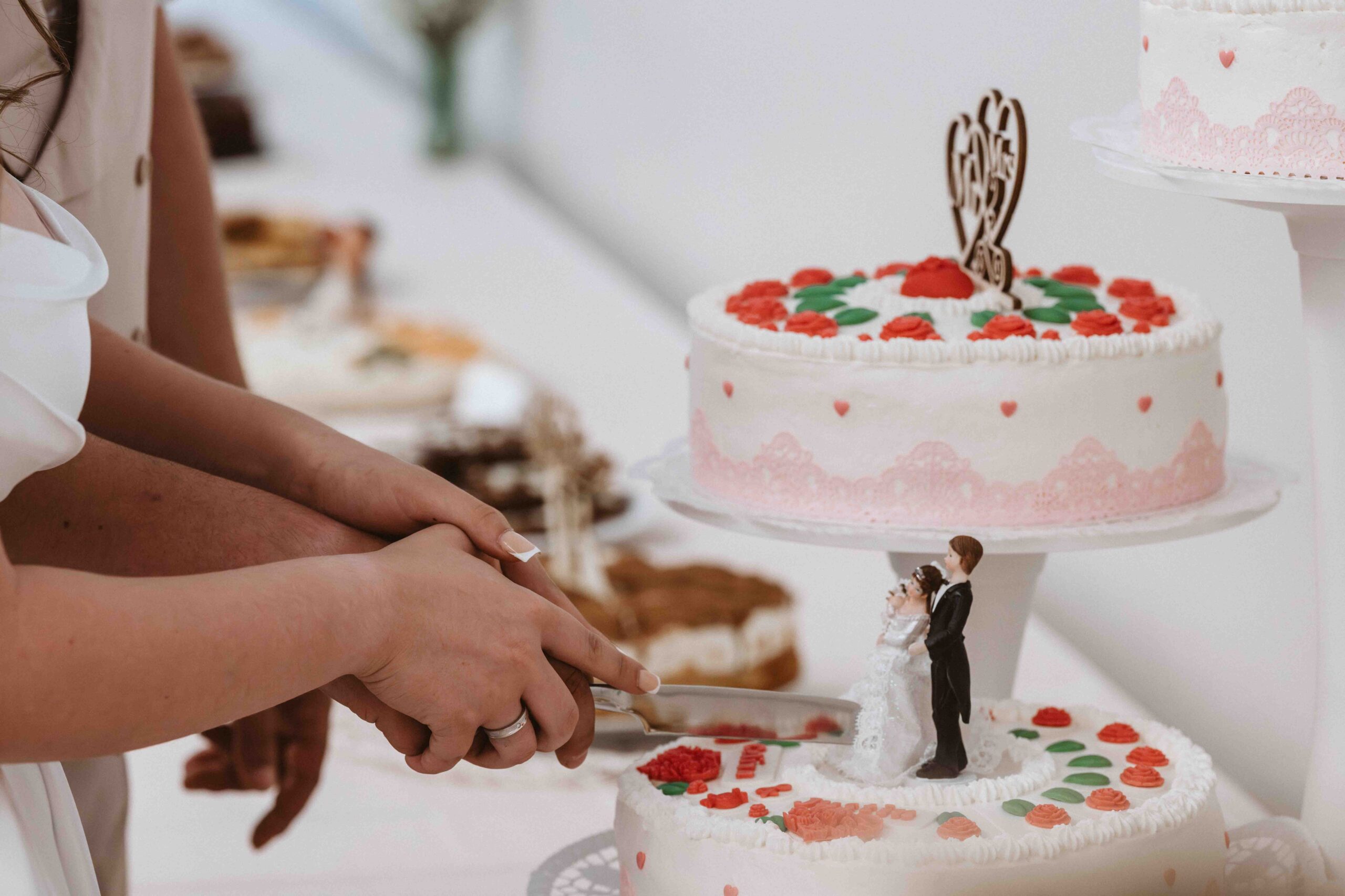 Hochzeitsreportage, Braut und Bräutigam schneiden gemeinsam die Hochzeitstorte an