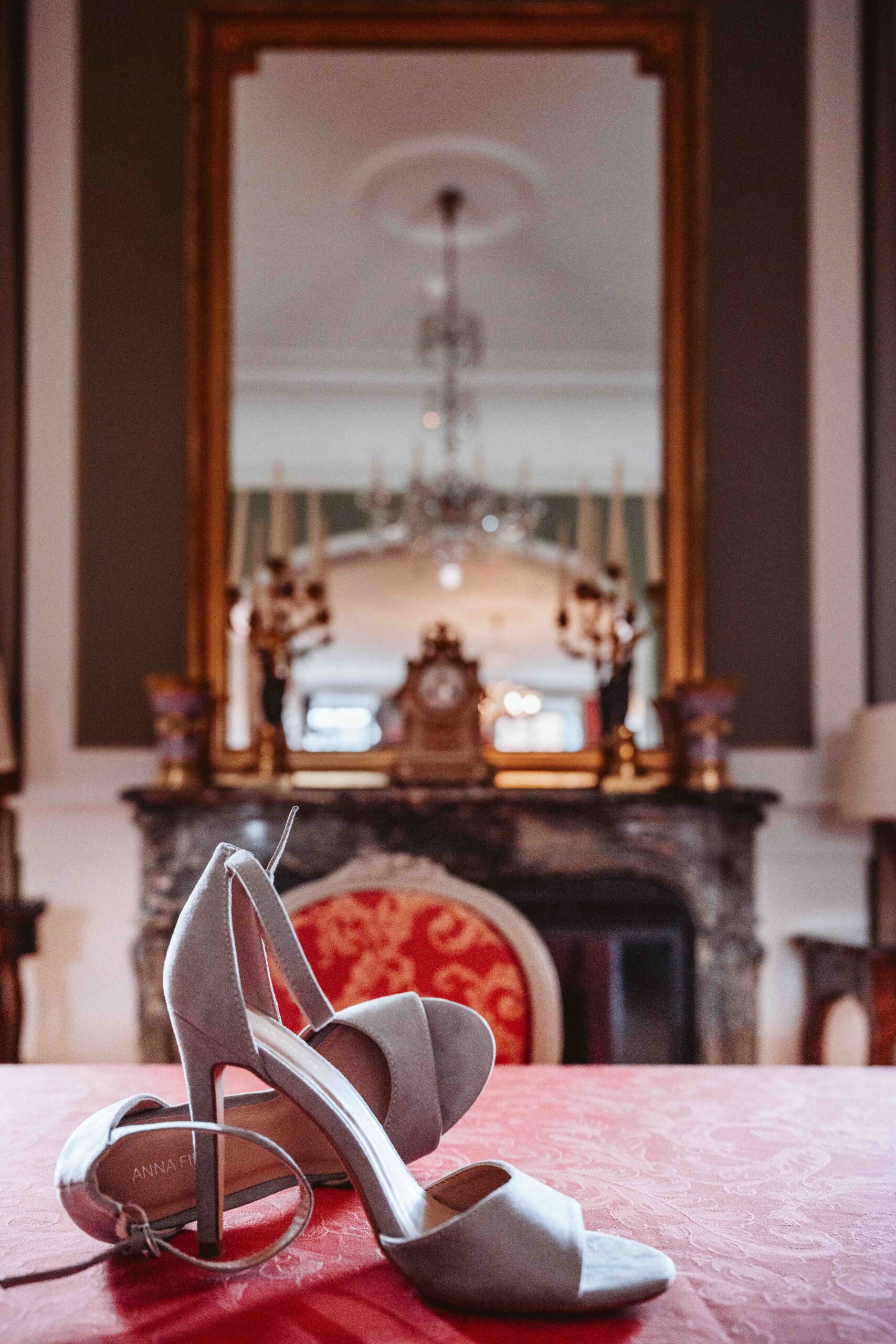 Elegante Brautschuhe stilvoll vor einem historischen Kamin während des Getting Readys fotografiert.