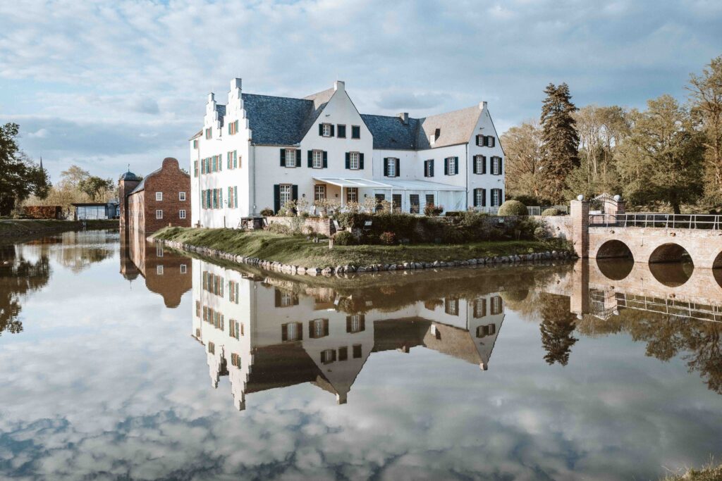 Historisches Hauptgebäude von Schloss Burg Heimerzheim mit Spiegelung im Wassergraben als elegante Hochzeitslocation in NRW.