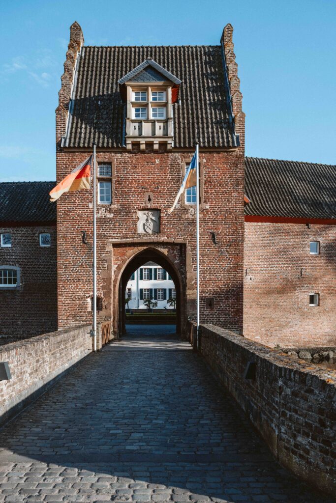 Historisches Torhaus von Schloss Burg Heimerzheim mit Brücke über dem Wassergraben und Blick auf die elegante Hochzeitslocation in NRW.