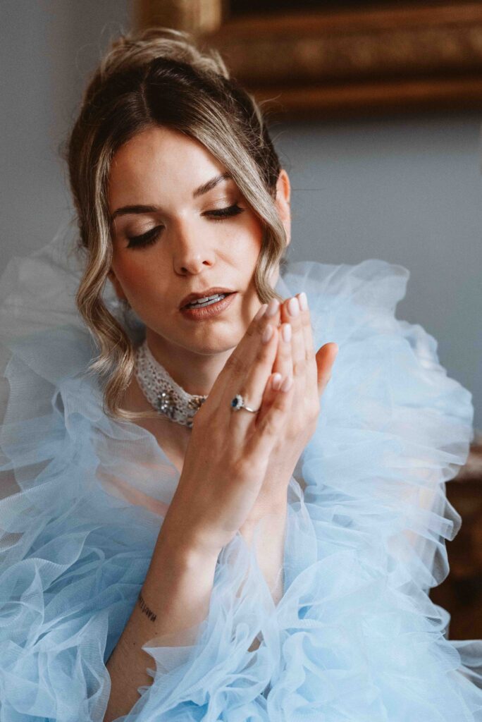 Elegantes Bridal Portrait einer Braut im Morgenmantel mit gesenktem Blick auf ihre Hände während eines Boudoir Shootings auf Schloss Burg Heimerzheim.