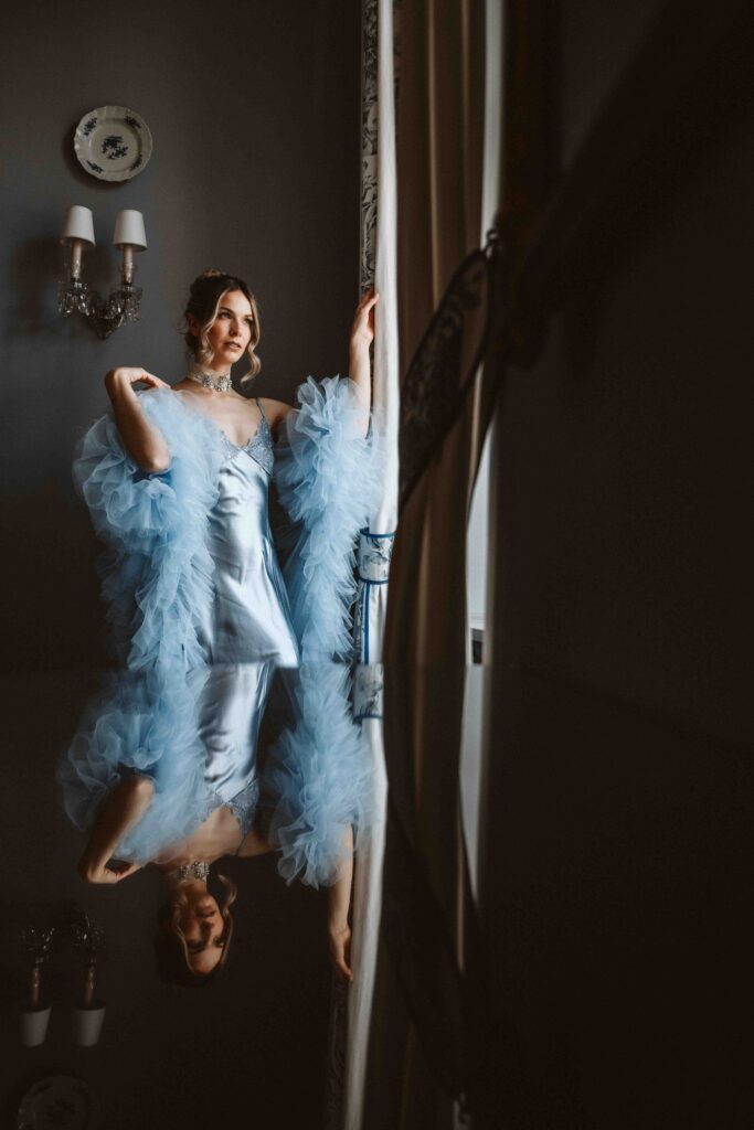 Elegantes Bridal Boudoir Portrait einer Braut am Fenster mit Spiegelung auf einem Tisch auf Schloss Burg Heimerzheim.