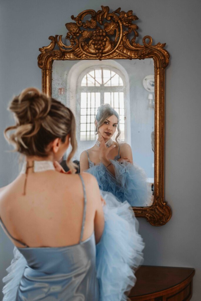 Rückenansicht einer Braut im Morgenmantel vor einem alten Vintage-Spiegel während eines Bridal Boudoir Shootings auf Schloss Burg Heimerzheim.