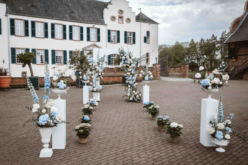 Blick durch florale Dekoration auf die Burg Heimerzheim während eines Editorial Styled Shootings mit freier Trauung.
