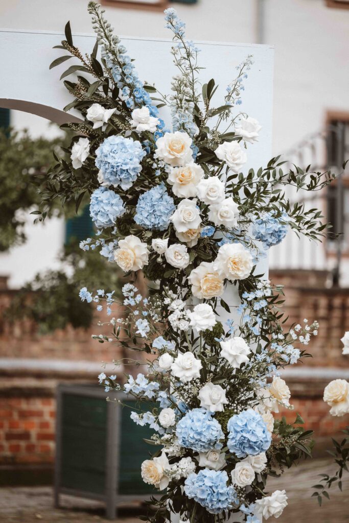 Detailaufnahme der floralen Hochzeitsdekoration am Traubogen vor Schloss Burg Heimerzheim mit weißen und rosafarbenen Blumenarrangements.
