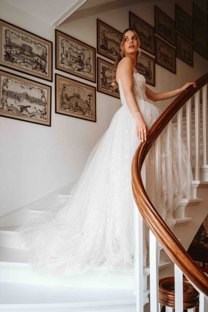 Elegantes Portrait einer Braut im Brautkleid auf der geschwungenen Treppe von Schloss Burg Heimerzheim im historischen Ambiente der Hochzeitslocation.