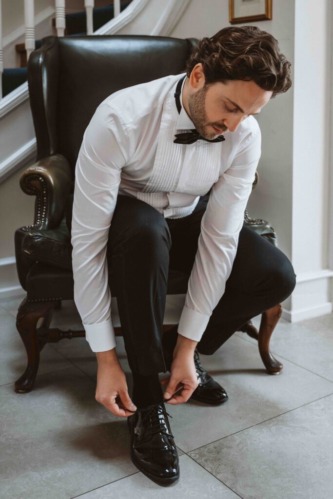 Bräutigam bindet seine Lackschuhe während des Getting Ready in der Villa Bodinus und bereitet sich auf die bevorstehende Trauung vor.