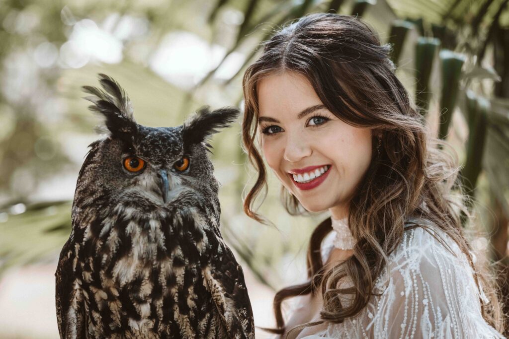 Lachende Braut mit großer Eule während eines Editorial Styled Shootings im Kölner Zoo.