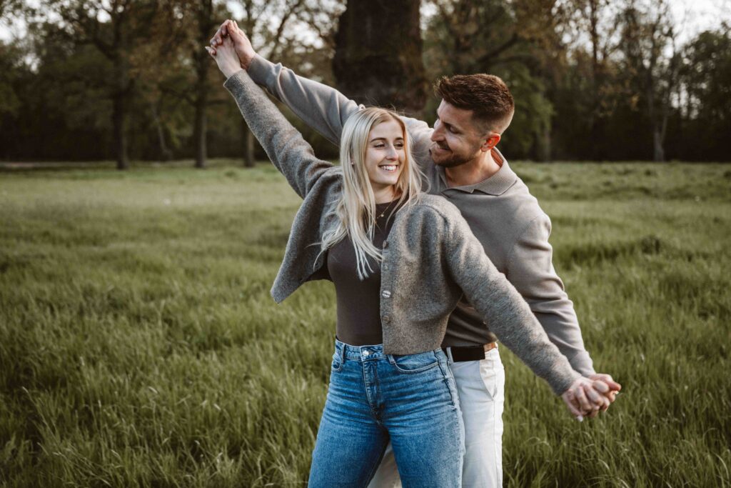 Verlobtes Paar genießt ein natürliches Engagement Shooting auf einer Wiese im warmen Abendlicht.