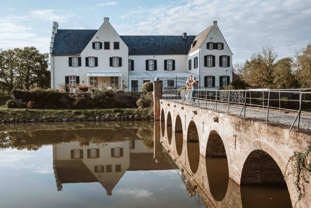 Paar beim Engagement Shooting auf der Brücke vor der Burg Heimerzheim mit Spiegelung im Wasser.