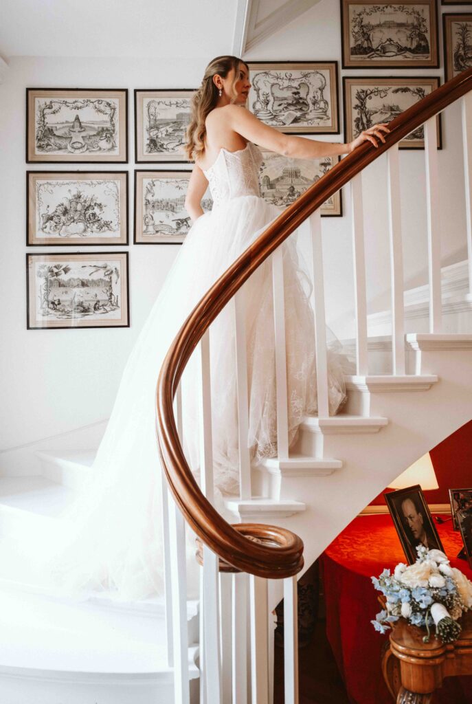 Braut im Brautkleid auf einer eleganten Treppe während des Getting Readys kurz vor der Hochzeit