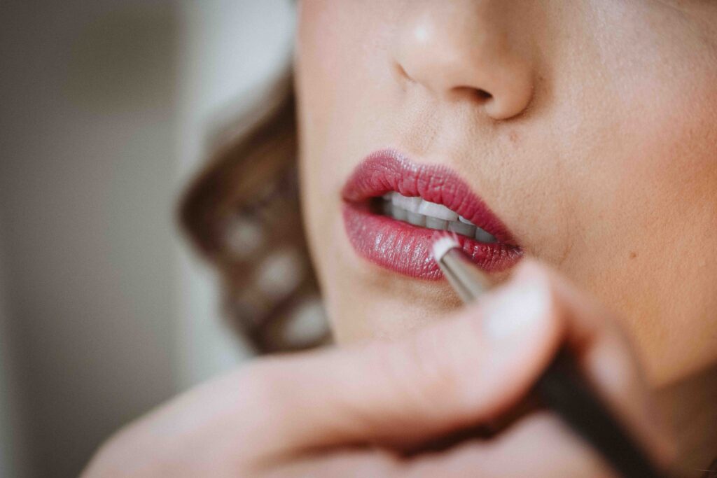 Nahaufnahme der Braut beim Auftragen des Lippenstifts während des Getting Readys vor der Hochzeit.