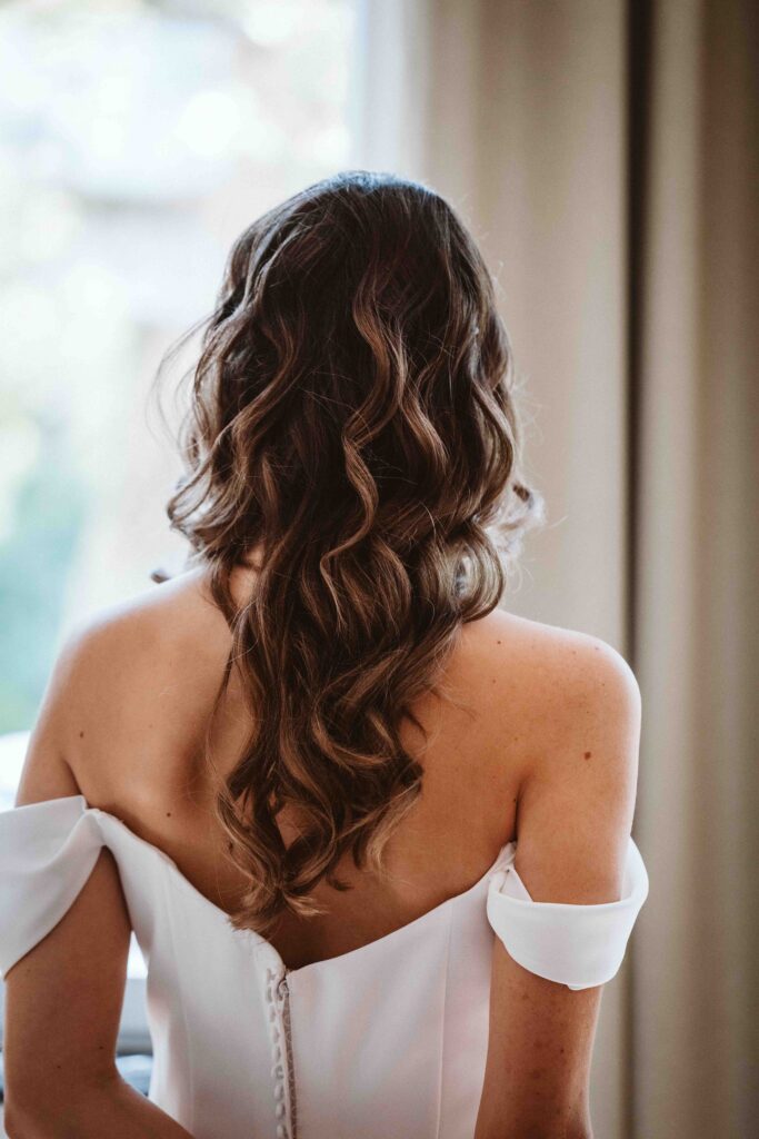 Rückansicht der Braut mit elegant gestylter Hochzeitsfrisur während des Gettings Ready vor der Trauung.
