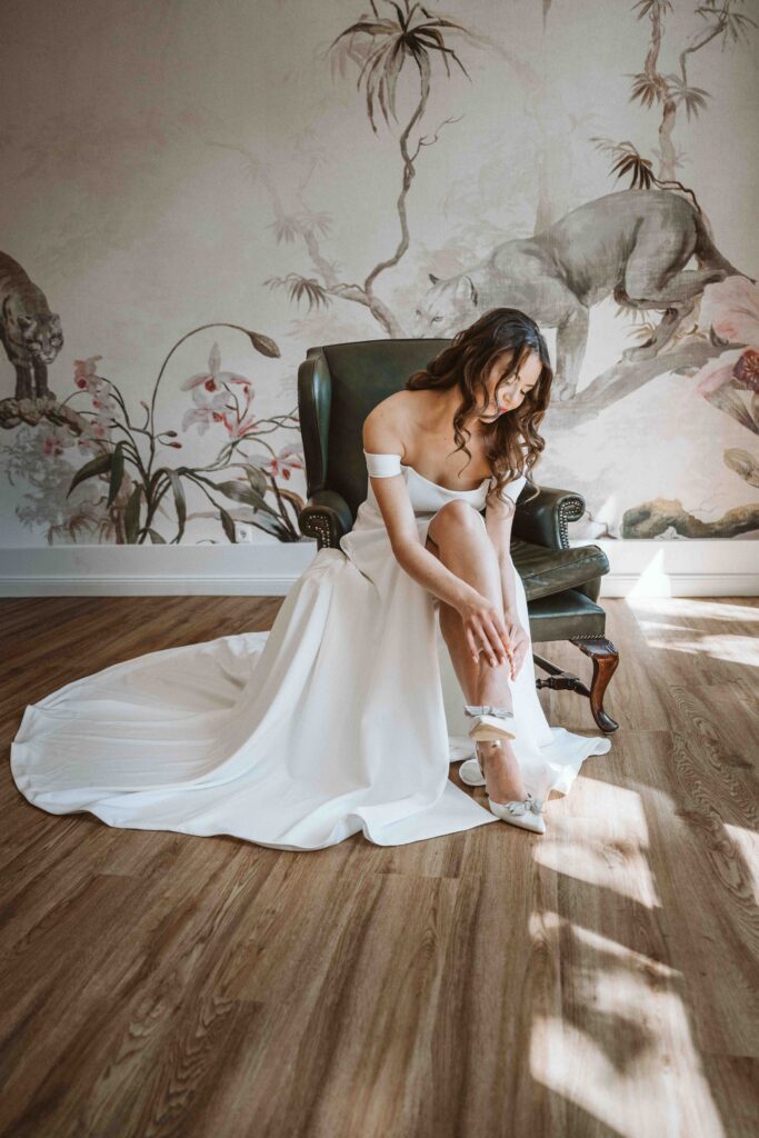 Braut zieht während des Gettings Ready ihre Hochzeitsschuhe an und bereitet sich auf die Trauung vor.