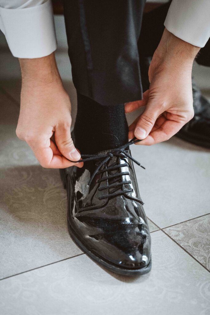 Nahaufnahme des Bräutigams beim Binden seiner eleganten Hochzeitsschuhe während des Gettings Ready.