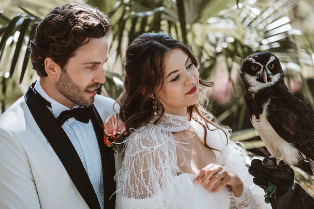 Braut und Bräutigam mit einem Brillenkauz bei einem Hochzeitsshooting in der Villa Bodinus im Kölner Zoo.