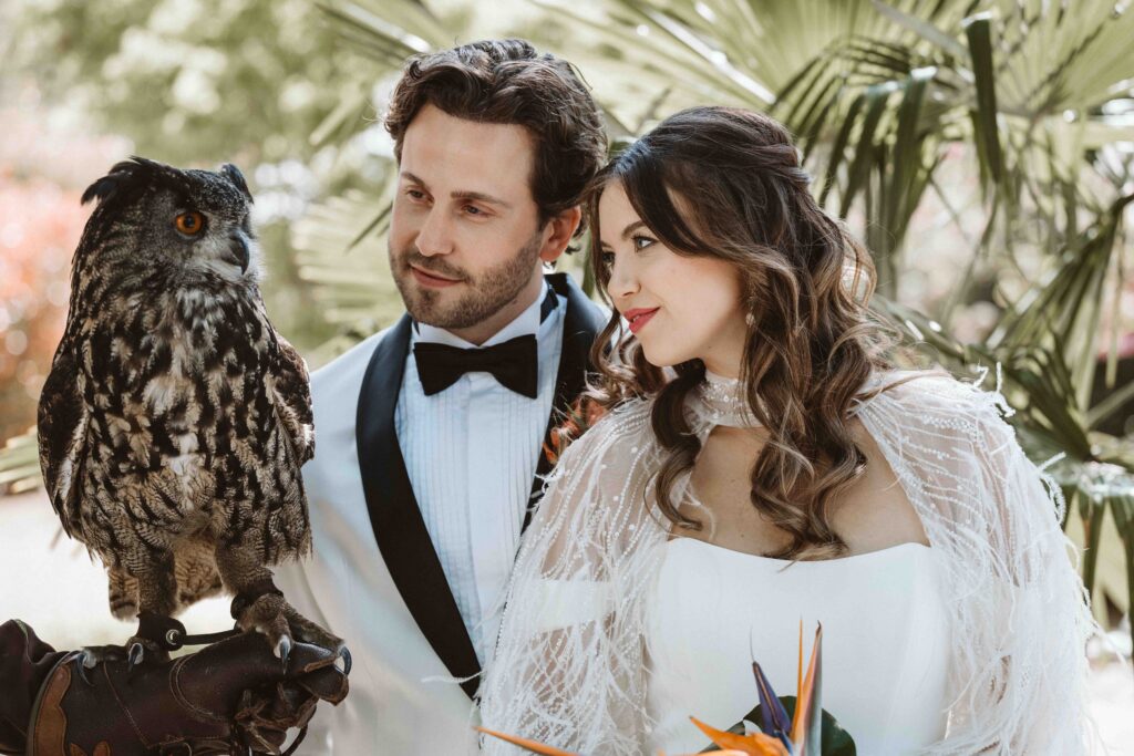 Braut und Bräutigam begegnen einem majestätischen Uhu aus der Falknerei während eines Hochzeitsshootings in der Villa Bodinus im Kölner Zoo.