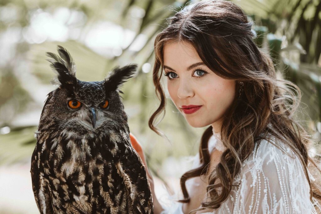 Braut mit einem majestätischen Uhu aus der Falknerei im Kölner Zoo während eines eleganten Hochzeitsshootings in der Villa Bodinus.