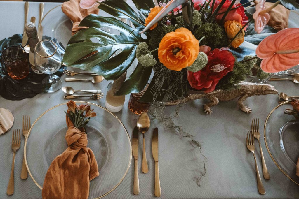 Draufsicht auf eine stilvoll dekorierte Hochzeitstafel mit tropischen Blumen und eleganten Details.