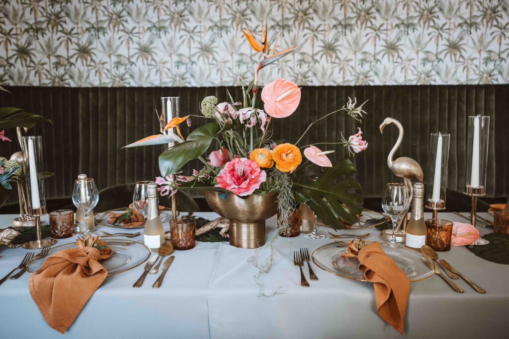 Blumenarrangement mit tropischen Blüten als Mittelpunkt der Hochzeitstafel.