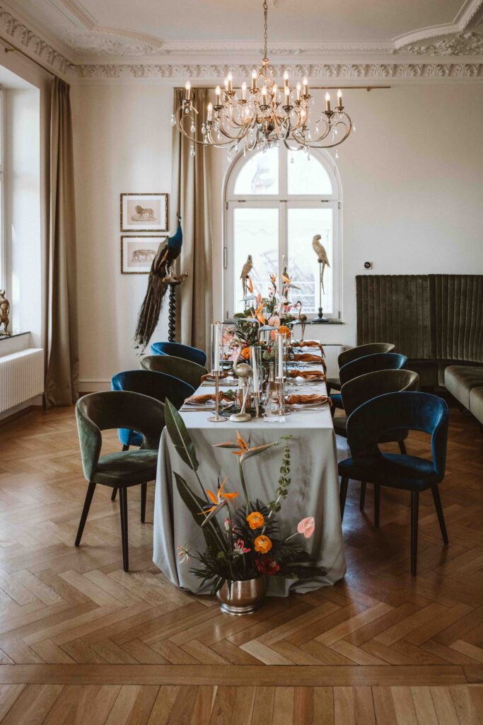 Festlich gedeckte Hochzeitstafel mit tropischer Blumendekoration im historischen Festsaal der Villa Bodinus im Kölner Zoo.