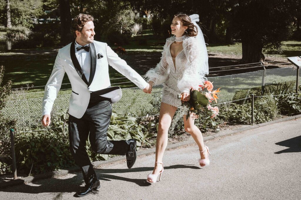 Brautpaar läuft Hand in Hand am Flamingogehege im Kölner Zoo während eines Styled Shootings